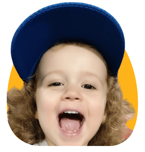 Close-up of a smiling toddler wearing a blue cap on a yellow background.